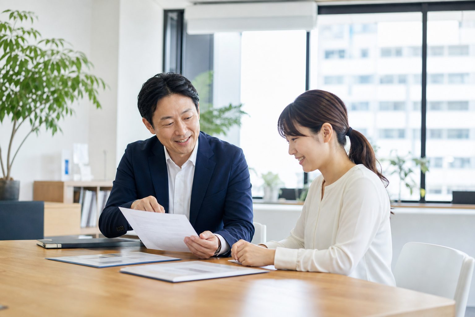 明るい事務所で、書類を見ながら和やかに打ち合わせをする代表